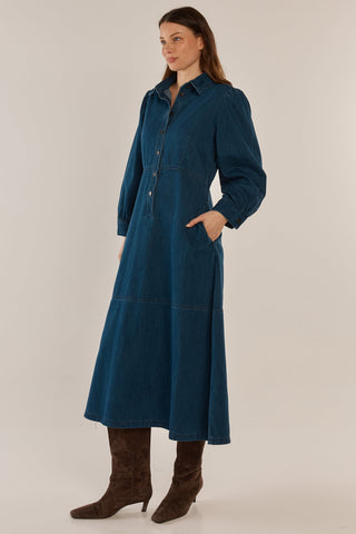Woman wearing a long-sleeved teal denim maxi dress and brown suede ankle boots.