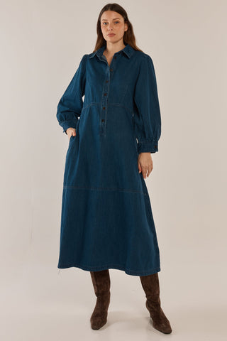 Woman wearing a long-sleeved blue denim maxi dress and brown suede boots.