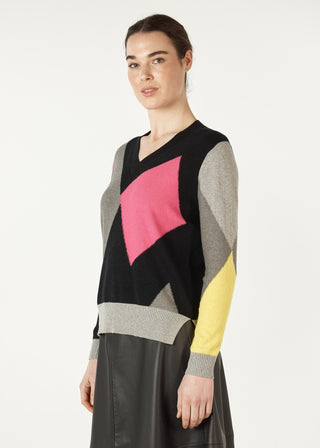 Woman wearing a colorful geometric pattern v-neck knit sweater and black leather skirt
