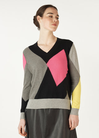 Woman wearing a colorful geometric pattern v-neck knit sweater and leather skirt.