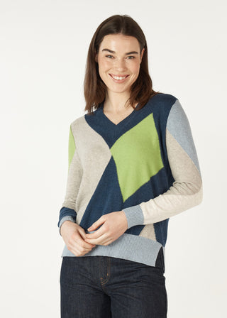 Woman wearing a colorful geometric pattern V-neck knit sweater and dark denim jeans.