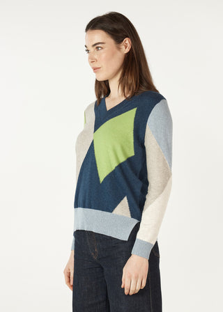 Woman wearing a geometric pattern v-neck knit sweater in blue, green, and cream tones.