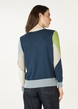 Woman wearing a navy blue color-block knit sweater with green and beige accents.