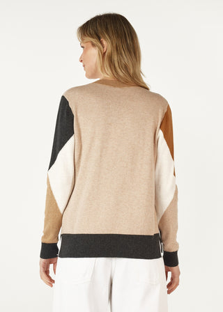 Woman wearing a multi-color colorblock knit sweater in beige, black, and tan tones.