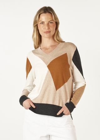 Woman wearing a geometric pattern V-neck knit sweater in tan, cream, and black tones.