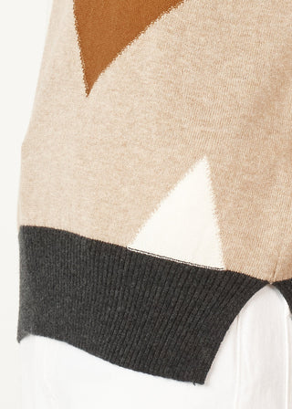 Close-up of a beige knit sweater featuring a geometric pattern in brown and white.