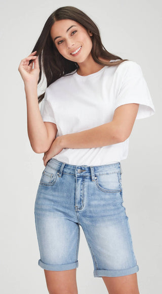Woman wearing a white t-shirt and light blue denim shorts.