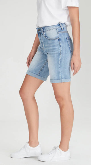 Woman wearing light wash blue denim shorts and white sneakers.