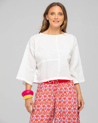 Woman wearing a white wide-sleeve top and red and white patterned wide-leg pants.
