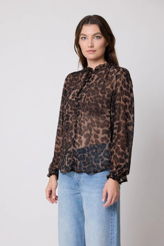Woman wearing a long-sleeve leopard print chiffon blouse and light blue denim jeans.