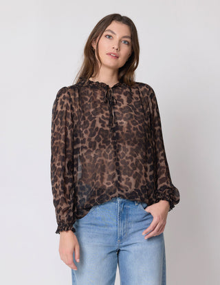 Woman wearing a brown leopard print sheer long sleeve blouse and blue denim jeans
