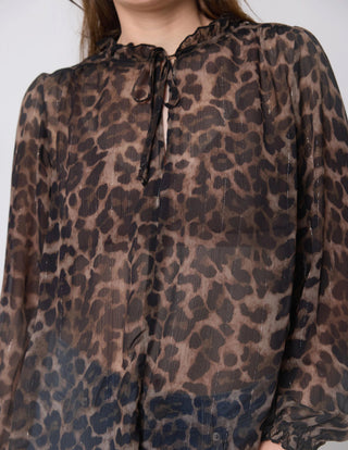 Woman wearing a sheer leopard print long sleeve blouse with a tie neck detail.