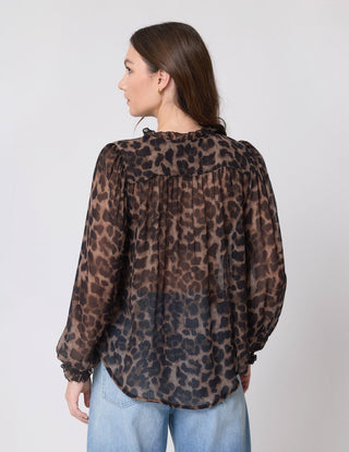 Woman wearing a brown leopard print long sleeve blouse and blue jeans.