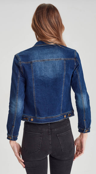 Rear view of a woman wearing a cropped blue denim jacket and black skinny jeans.