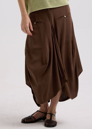 Woman wearing a brown midi skirt with pockets and black strappy sandals.