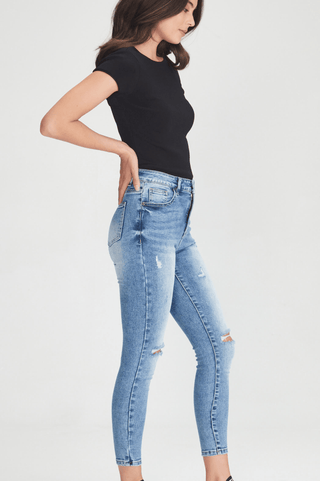 Woman wearing a black t-shirt and light wash ripped skinny jeans.