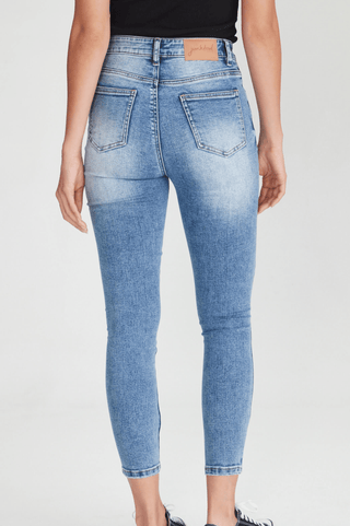 Back view of a woman wearing light wash blue skinny jeans with back pockets.