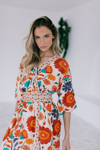 Woman wearing a floral print V-neck maxi dress with colorful orange and blue flower patterns.