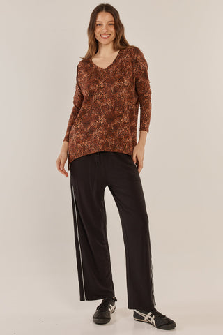 Woman wearing a brown leopard print V-neck top and black wide-leg track pants with side stripes.