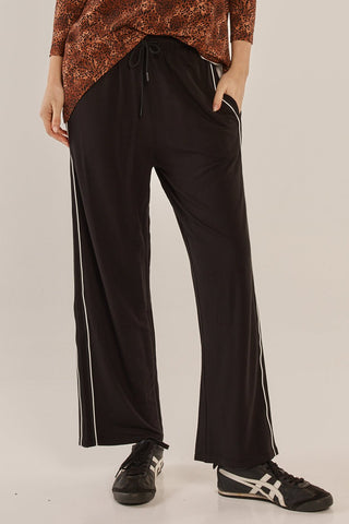Woman wearing black wide-leg lounge pants with white side stripes and leopard print top.