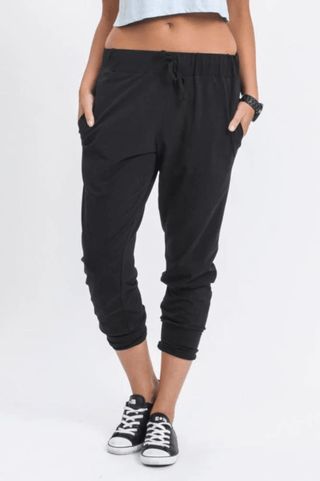 Woman wearing black cropped joggers and black canvas sneakers.