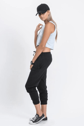 Woman in light blue crop top, black joggers, and baseball cap for casual leisure wear.