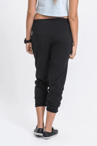 Woman wearing black cropped joggers and black slip-on sneakers.