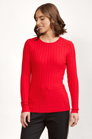 Woman wearing a bright red long-sleeve ribbed knit top and black joggers.
