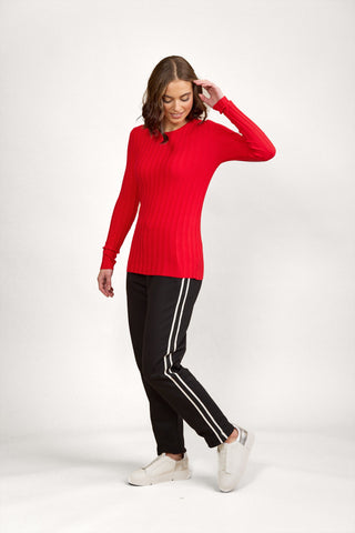 Woman wearing a red ribbed long sleeve top and black joggers with white side stripes.