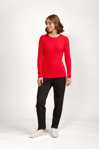 Woman wearing a red ribbed long sleeve top and black joggers with side stripes.