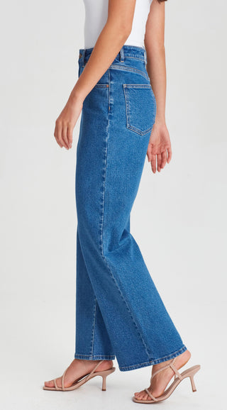 Woman wearing high-waisted blue wide-leg denim jeans and nude strappy heeled sandals.