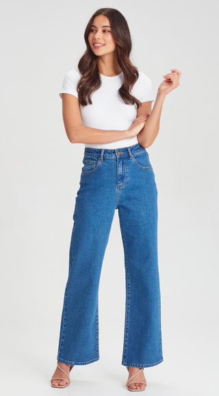 Woman wearing a white t-shirt and blue wide-leg denim jeans.