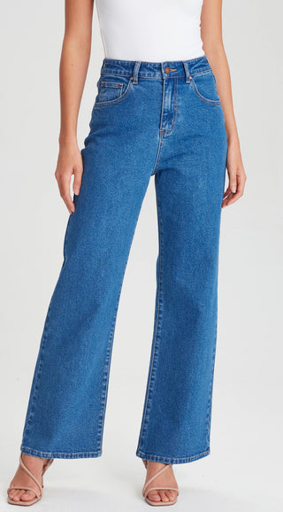 Woman wearing blue high-waisted wide leg denim jeans and beige strappy sandals.