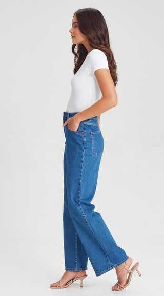 Woman wearing a white short sleeve t-shirt and blue wide leg denim jeans.