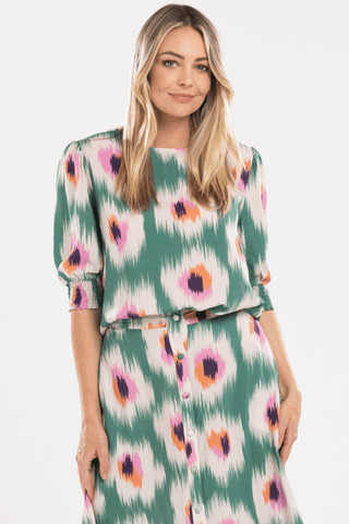 Woman wearing a green ikat print button-down midi dress with short puff sleeves.