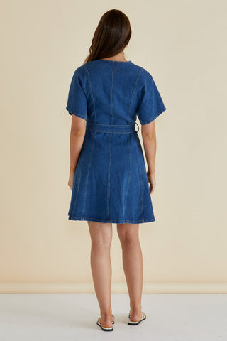 Back view of a woman wearing a short sleeve blue denim dress with a belted waist.