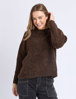 Woman wearing a brown fuzzy knit sweater and black jeans.