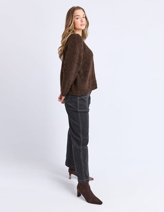 Woman wearing a brown fuzzy knit sweater, dark grey cargo pants, and brown ankle boots.