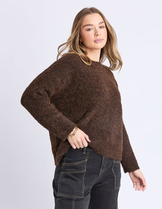 Woman wearing a brown textured knit sweater and black cargo pants.