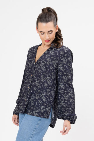 Woman wearing a navy blue long sleeve floral print button-up blouse and blue jeans.
