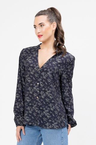 Woman wearing a black long-sleeve floral print button-up blouse and blue jeans.