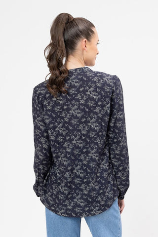 Woman wearing a navy blue long sleeve floral print blouse and light blue jeans.
