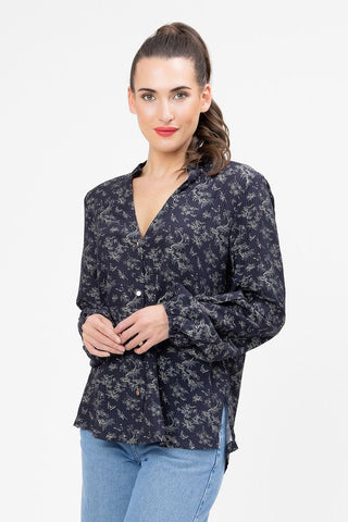 Woman wearing a navy blue floral long sleeve button-up blouse and light blue jeans.