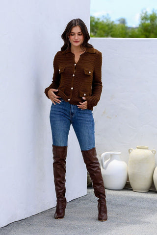 Woman wearing a brown button-up knit cardigan, blue jeans, and brown over-the-knee boots.