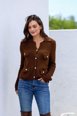 Woman wearing a brown textured knit cardigan and blue denim jeans.