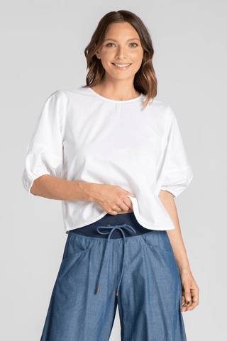 Woman wearing a white puff sleeve blouse and blue denim wide-leg lounge pants.