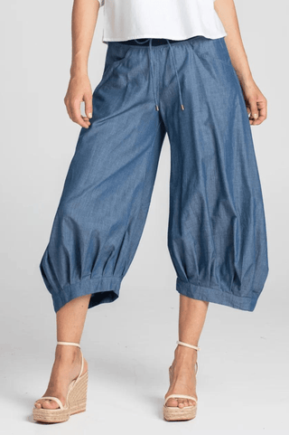 Woman wearing blue denim wide-leg cropped culottes with drawstring waist and wedge sandals.