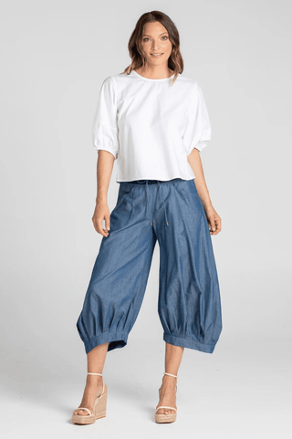 Woman wearing a white puff sleeve blouse and blue denim cropped wide-leg pants.