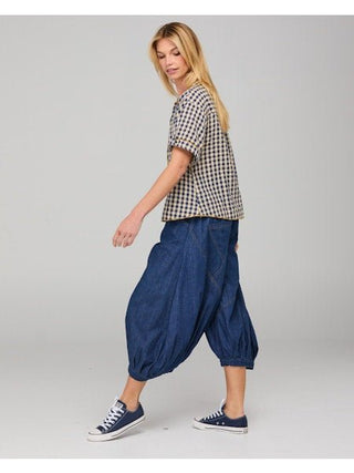 Woman wearing a gingham check t-shirt and blue denim harem pants with sneakers.