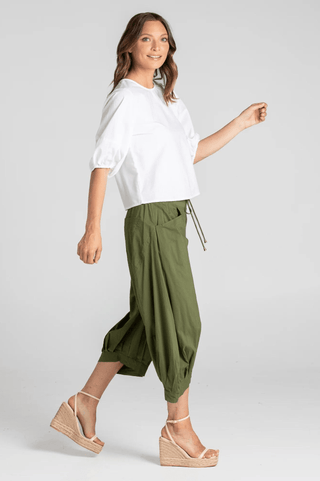 Woman wearing a white puff sleeve blouse and olive green wide leg cropped pants with wedge sandals.